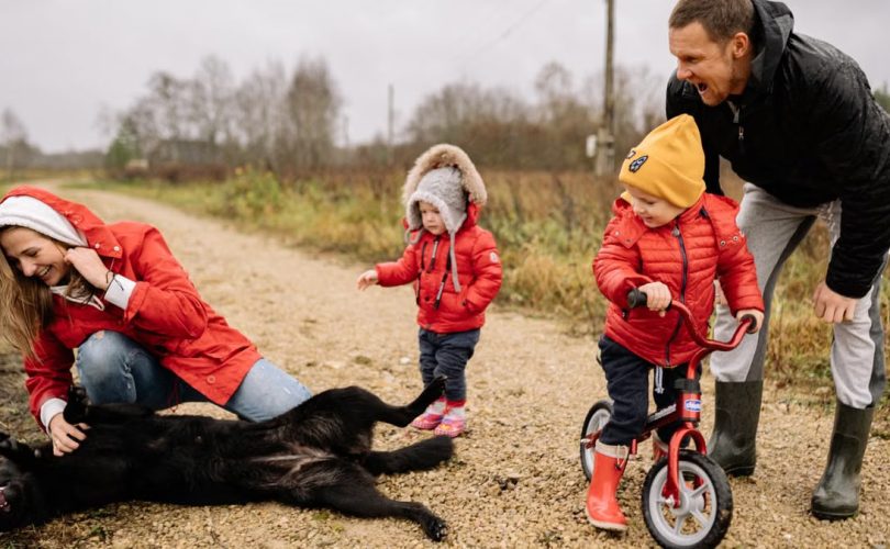 Happy family enjoying quality time outdoors with kids and dog in countryside.